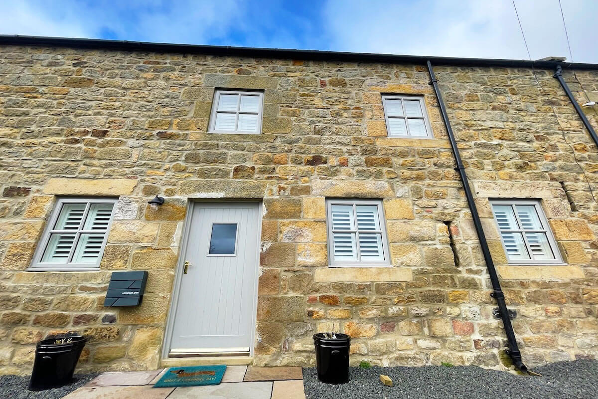 Sage, wooden window shutter blinds in traditional farmhouse style building.