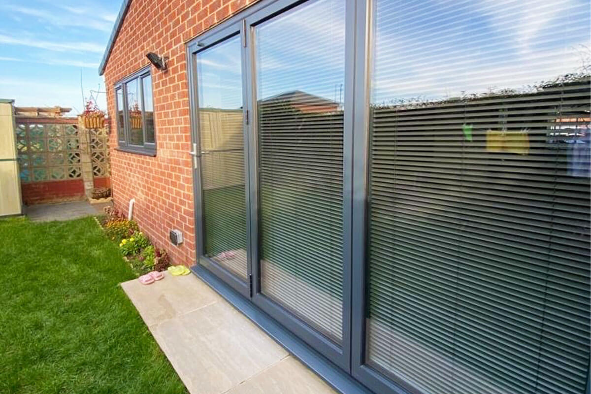 Grey venetian blinds in modern bi-fold doors.