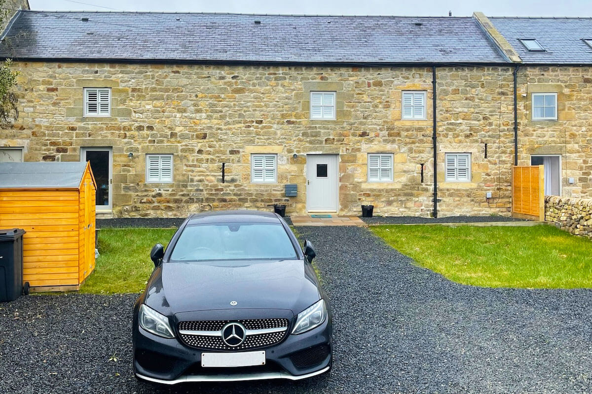 Large farmhouse with sage coloured wooden shutter blinds in all windows.