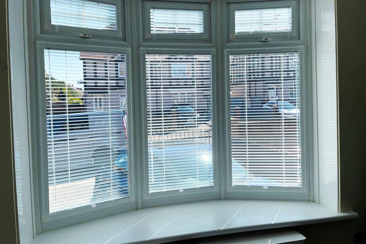White venetian shutter blinds in bay window.