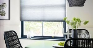 Pleated Blinds Are Perfect For Any Room. Grey window blinds half open showing outdoor garden area in modern dining area.