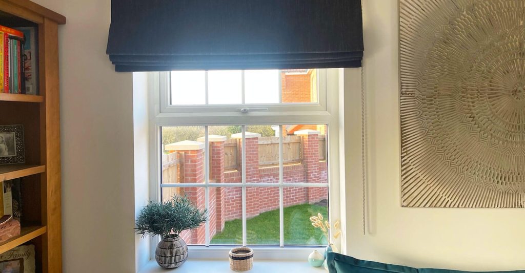 Roman blind on window in living room, including blackout blinds.